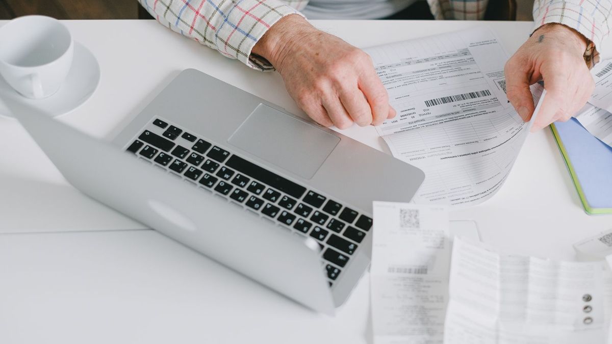 Hands sorting paperwork next to a laptop